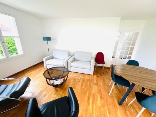 a living room with a table and chairs at Appartement standing avec jardin, 4 personnes, stratégiquement situé in Mantes-la-Jolie