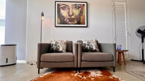 a living room with a couch and a painting on the wall at Flip Flops Villa in Yzerfontein