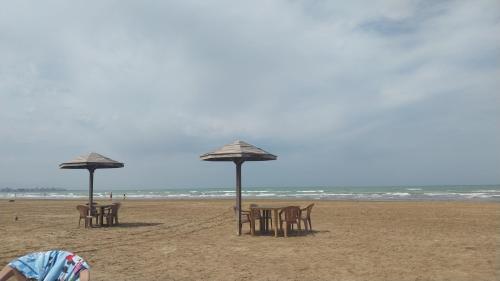a group of tables and umbrellas on a beach at Banu House in Sumqayyt