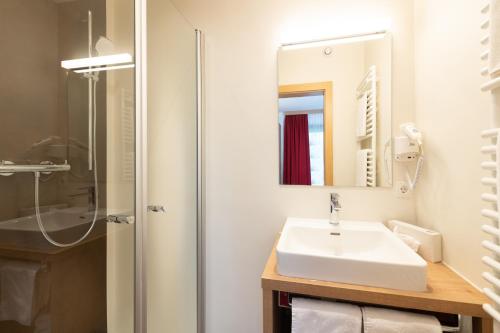 a bathroom with a sink and a shower at Hotel Gasthof Kröll Nationalpark-Card, Bergbahnen, Großglockner, Restaurant mit regionaler Küche in Niedernsill