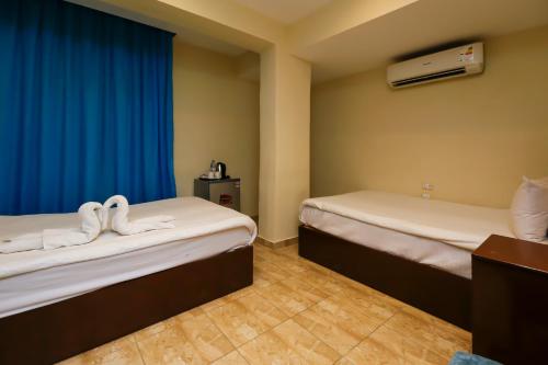 two beds in a room with blue curtains at Pyramids Glory Inn in Cairo