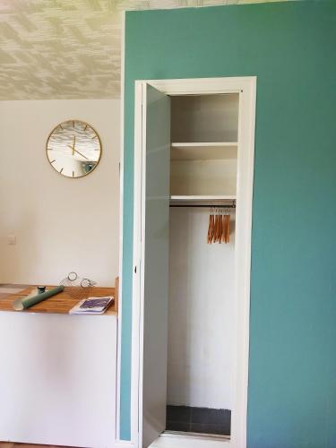 a door to a closet with a clock on a wall at studio du parc piscine in Souillac