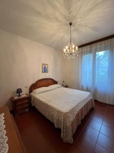 Un dormitorio con una cama grande y una lámpara de araña. en Appartamento Bosco in Città, en Cadè