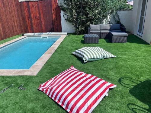 une cour avec une piscine et deux parasols dans l'établissement Maison climatisée, piscine, à 5 minutes des Grands Buffets, à Narbonne