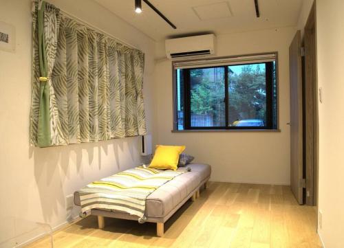 a room with a bed with a yellow pillow on it at 高円寺中野Villa in Tokyo