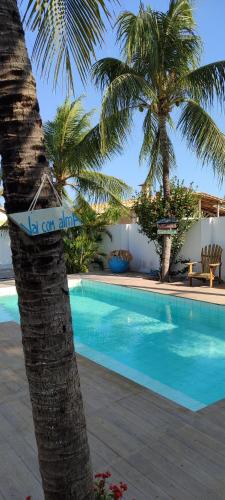 a swimming pool in front of a resort with palm trees at Pontal Praia Suítes in Fortim