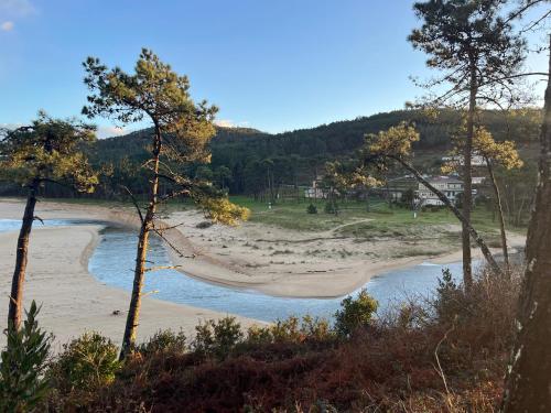 a hammock on a beach next to the water at Hostal Barco da Vella in Merejo