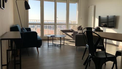 un salon avec un canapé, une table et des chaises dans l'établissement Une chambre privée bleu dans un appartement partagé, à Orléans