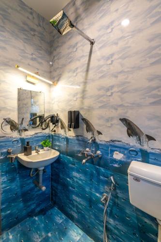 a bathroom with a sink and dolphins on the wall at Whoopers Boutique Hotel Morjim in Morjim