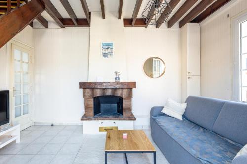 un salon avec un canapé bleu et une cheminée dans l'établissement La Maison Cabourgeaise proche mer, à Cabourg