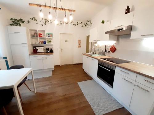 a kitchen with white cabinets and a sink and a table at Große Altbauwohnung auf dem Land in Kallham