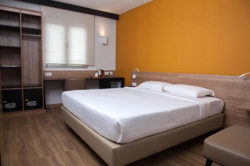 a bedroom with a large white bed and a desk at Dunia Hôtel Bamako ACI 2000 in Bamako