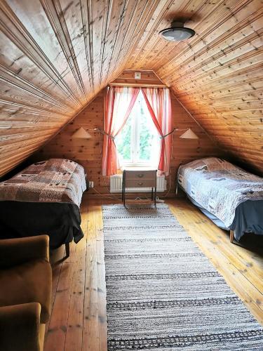 a attic bedroom with two beds and a window at Bond-Gården in Fågelmara