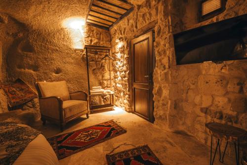 a room with a bed and a chair and a door at Lubberona Cave Cappadocia in Nar