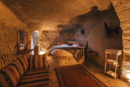 a bedroom with a bed and a couch in a cave at Lubberona Cave Cappadocia in Nar