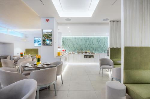 a dining room with tables and chairs and a kitchen at Hotel Gardenia Sorrento, Ascend Hotel Collection in Sorrento