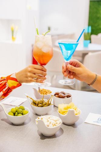 two people holding cocktails on a table with snacks at Hotel Gardenia Sorrento, Ascend Hotel Collection in Sorrento