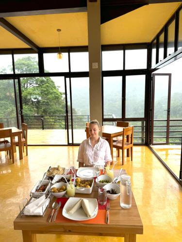 a woman sitting at a table with food on it at Aqua Dunhinda Villa in Kandy