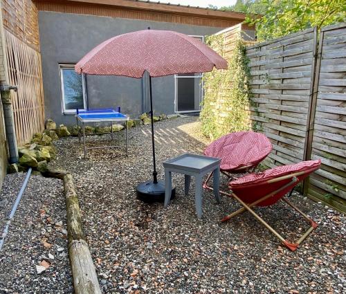 a patio with a table and an umbrella and chairs at Petite maison au calme avec jardin clôturé les animaux bienvenue in Mollau
