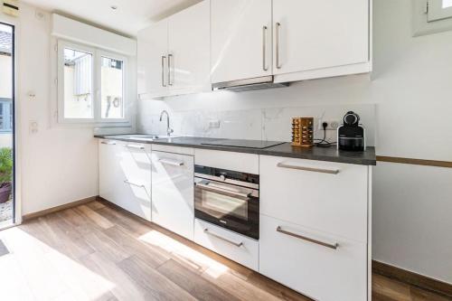 eine weiße Küche mit weißen Schränken und schwarzen Arbeitsplatten in der Unterkunft Paris La Defense - Refurbished independent house in La Garenne-Colombes