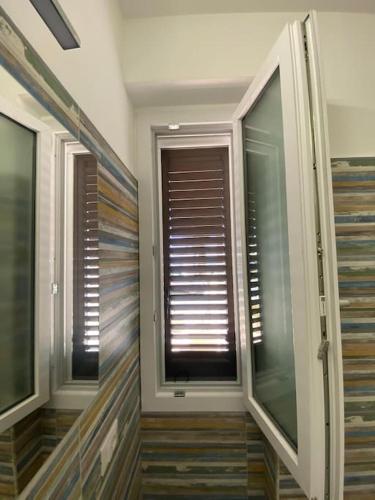 a room with two windows and a window with blinds at Casa Plumeria in Marinella di Selinunte