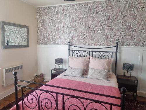 a bedroom with a bed with pink sheets and a wallpaper at L'AnciennePoste in Bugeat