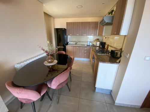 a kitchen with a table and some pink chairs at Panorama Apartment Zone Touristique Haut Standing in Mahdia