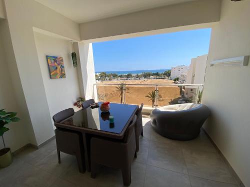 a living room with a table and a chair and a window at Panorama Apartment Zone Touristique Haut Standing in Mahdia