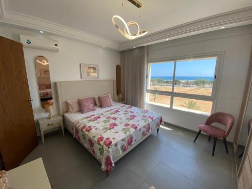 a bedroom with a bed and a large window at Panorama Apartment Zone Touristique Haut Standing in Mahdia