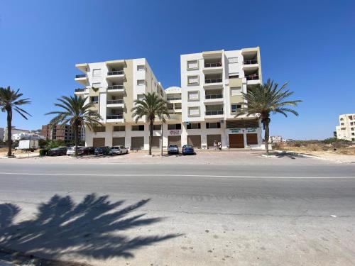 an empty street in front of a building with palm trees at Panorama Apartment Zone Touristique Haut Standing in Mahdia