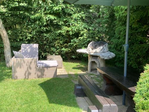 a garden with a bench and a chair and an umbrella at Liptovská Drevenica in Liptovský Mikuláš