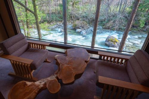 a living room with a view of a river from a window at Wanosato in Takayama
