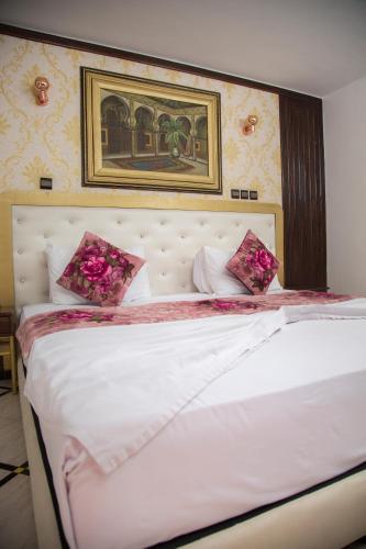 a bedroom with a white bed with pink flowers on it at Hotel Al Kabir in Marrakech