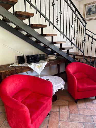 a living room with two red chairs and stairs at Ca' Rivella - paceful country living in Villa dʼAiano