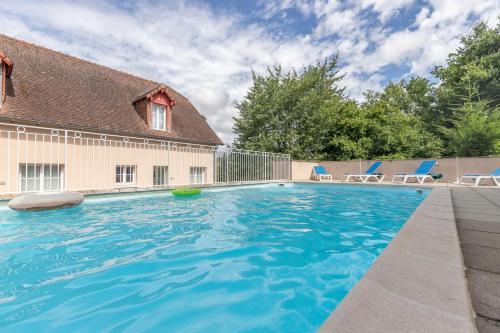 une piscine avec des chaises bleues et une maison dans l'établissement Grand Studio Le Bleu Posay, à La Roche-Posay
