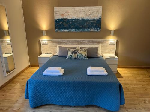 a bedroom with a blue bed with two towels on it at Hostal Barco da Vella in Merejo