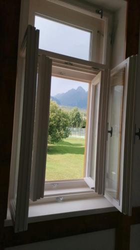 a window with a view of a green field at Apartmán Srnka s výhľadom na Vysoké Tatry in Smokovce
