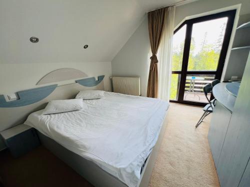 a bedroom with a bed and a desk and a window at Ski Chalet Sinaia in Sinaia