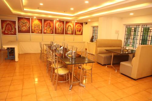 Sri Kamalanivas في فيلوري: غرفة طعام بها طاولات وكراسي ولوحات على الجدران