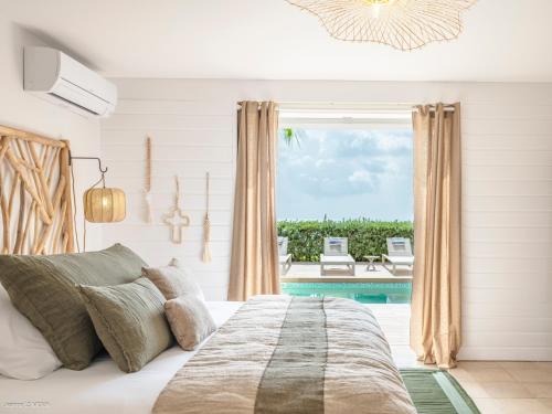 a bedroom with a bed and a view of a pool at Be Happy à pied de Friar's Bay face au coucher de soleil in Friar's Bay