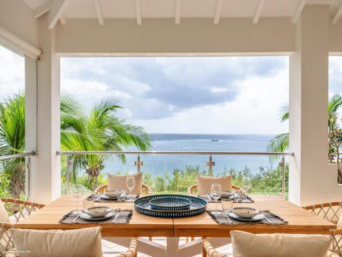 a dining room with a table and a view of the ocean at Be Happy à pied de Friar's Bay face au coucher de soleil in Friar's Bay