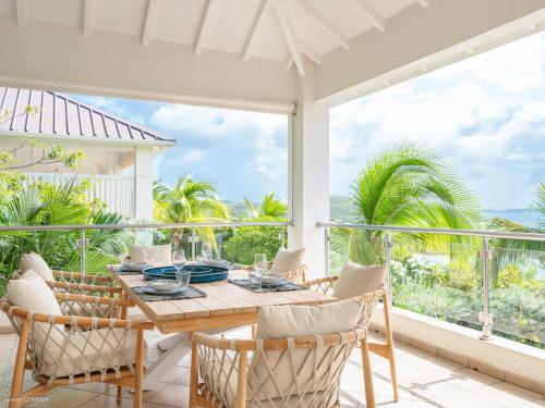 a dining room with a table and chairs and a large window at Be Happy à pied de Friar's Bay face au coucher de soleil in Friar's Bay