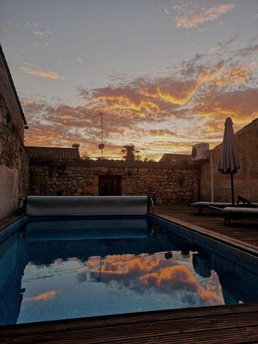une piscine avec un coucher de soleil en arrière-plan dans l'établissement Maison de Maître Elegia, à Castillon-la-Bataille