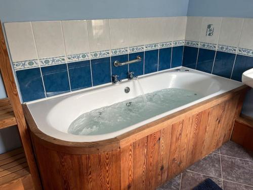 a bath tub in a bathroom with blue tiles at Bryn Rhedyn cottage in Cwm-y-glo
