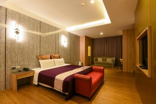 a hotel room with a bed and a red chair at Belle Song Motel in Shulin