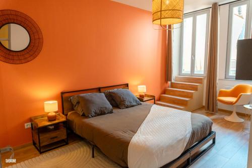 a bedroom with a bed with an orange wall at Hypercentre, spacieux, authentique - Le haut Saugeais in Pontarlier
