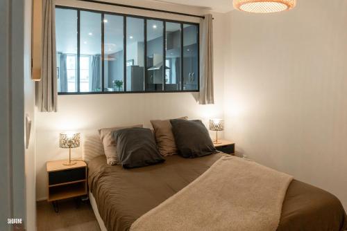 a bedroom with a bed with a window and two lamps at Hypercentre, spacieux, authentique - Le haut Saugeais in Pontarlier