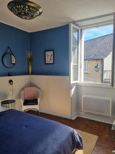 a bedroom with blue walls and a bed and a window at L'AnciennePoste in Bugeat