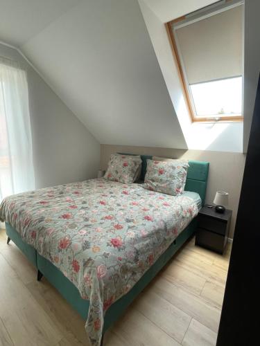 a bedroom with a bed with a floral bedspread and a window at Villapark Vonyarcvashegy Libella in Vonyarcvashegy