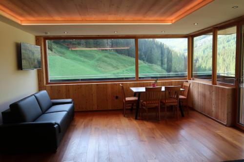 a living room with a table and chairs and a large window at Rumwaldhof - Wohnung Calendula in Solda